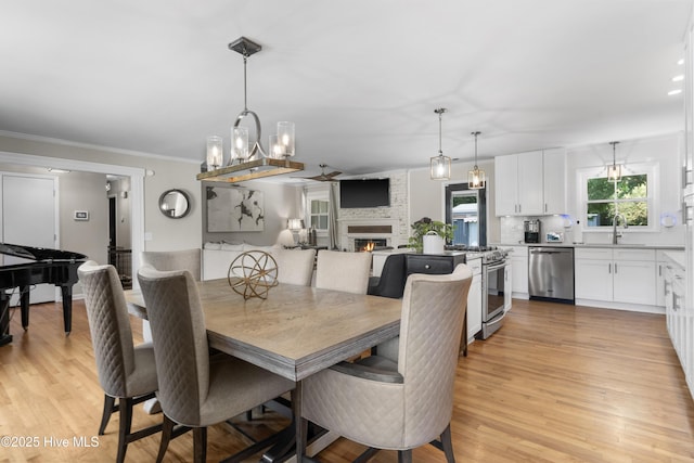 dining area with crown molding, an inviting chandelier, light wood finished floors, and a fireplace