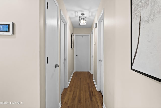 corridor with baseboards and dark wood-style flooring