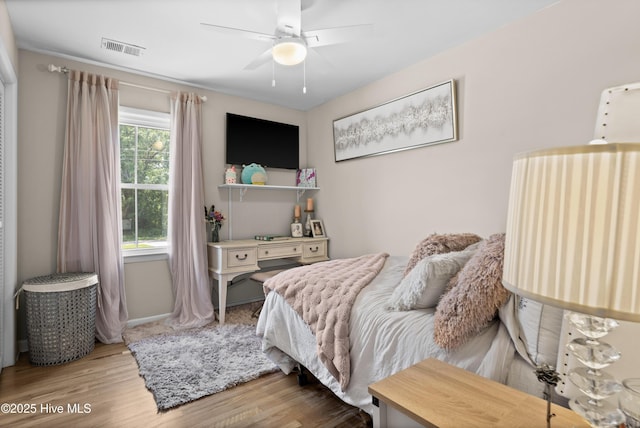 bedroom with baseboards, ceiling fan, visible vents, and wood finished floors