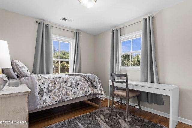 bedroom featuring baseboards, wood finished floors, and visible vents