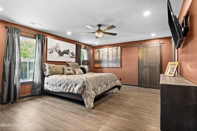 bedroom featuring visible vents, wood finished floors, ceiling fan, recessed lighting, and a barn door