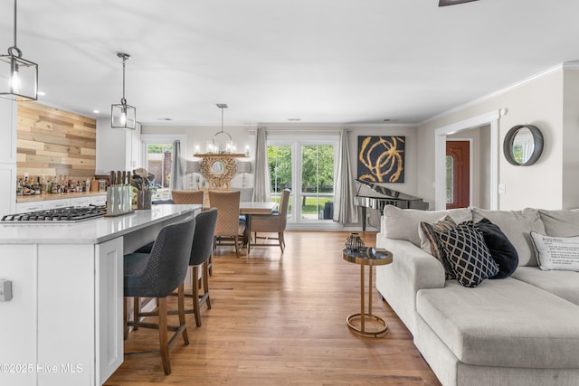 living room featuring light wood-style floors, ornamental molding, and an inviting chandelier