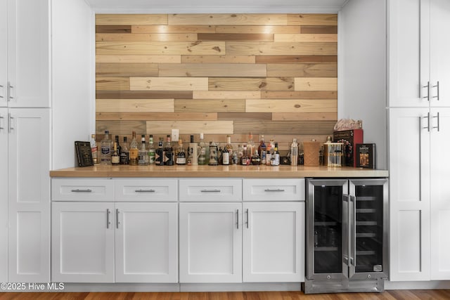 bar with a bar, wine cooler, and wooden walls