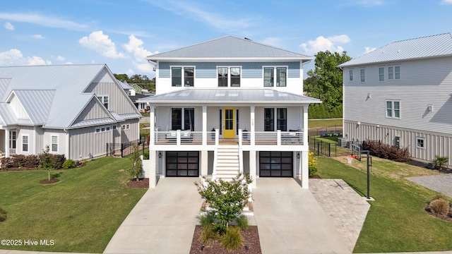 729 Waterstone Dr, Wilmington, NC 28411 - raised beach house featuring driveway, a front lawn, covered porch, an attached garage, and a standing seam roof