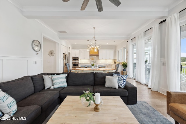 729 Waterstone Dr, Wilmington, NC 28411 - living area featuring beamed ceiling, a chandelier, a decorative wall, a ceiling fan, and crown molding
