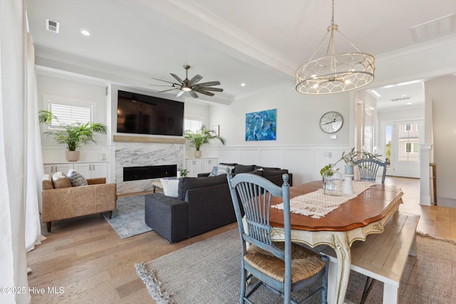729 Waterstone Dr, Wilmington, NC 28411 - dining space featuring light wood-type flooring, a high end fireplace, a ceiling fan, crown molding, and a decorative wall