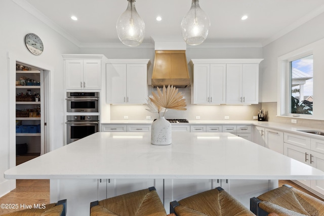 729 Waterstone Dr, Wilmington, NC 28411 - kitchen featuring a breakfast bar, light countertops, double oven, white cabinets, and crown molding