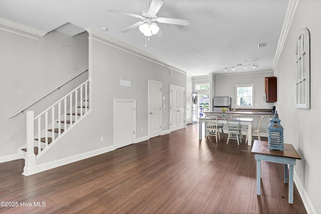 living area with ornamental molding, wood finished floors, baseboards, ceiling fan, and stairway