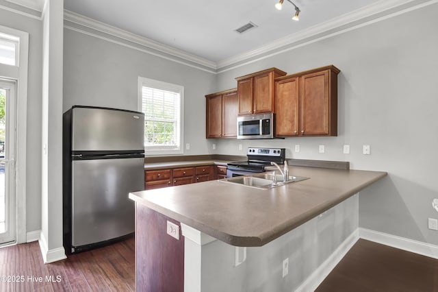 kitchen with visible vents, brown cabinetry, a peninsula, a sink, and appliances with stainless steel finishes