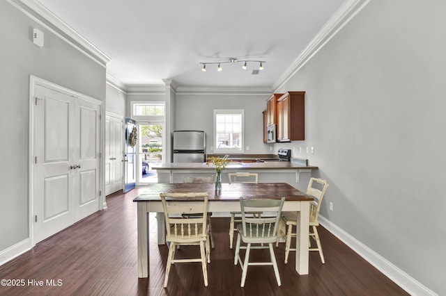 kitchen featuring dark wood-type flooring, ornamental molding, appliances with stainless steel finishes, and a peninsula