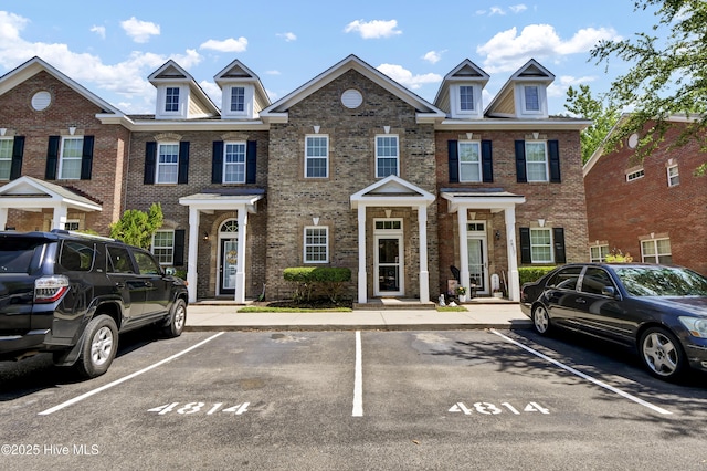 multi unit property featuring brick siding and uncovered parking
