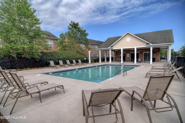 pool with a patio, an outdoor structure, and fence