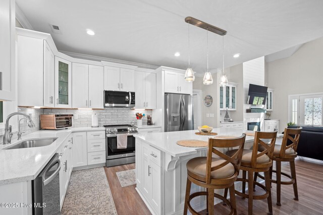 kitchen featuring appliances with stainless steel finishes, a center island, a sink, a toaster, and a breakfast bar