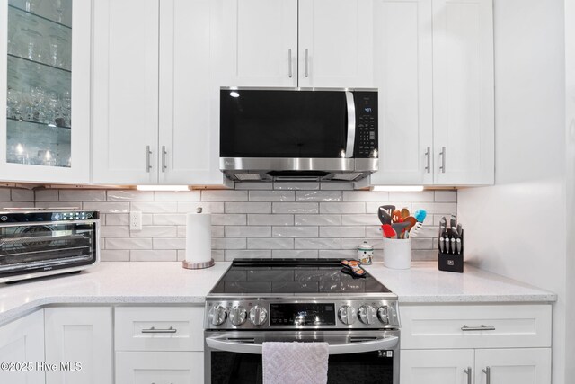 kitchen with a toaster, glass insert cabinets, stainless steel appliances, and white cabinetry