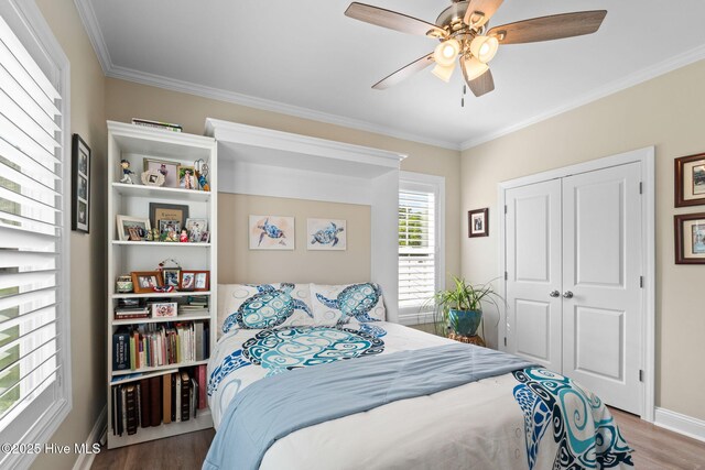 bedroom with crown molding, a ceiling fan, baseboards, wood finished floors, and a closet