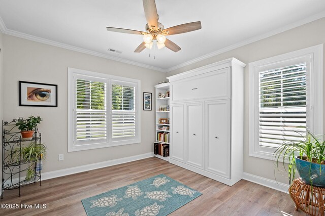 living area featuring light wood-style floors, a ceiling fan, baseboards, and ornamental molding
