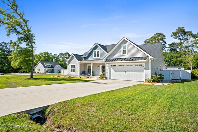 view of front of property featuring a porch, a front yard, a standing seam roof, driveway, and metal roof