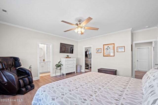 bedroom with visible vents, crown molding, wood finished floors, baseboards, and a spacious closet
