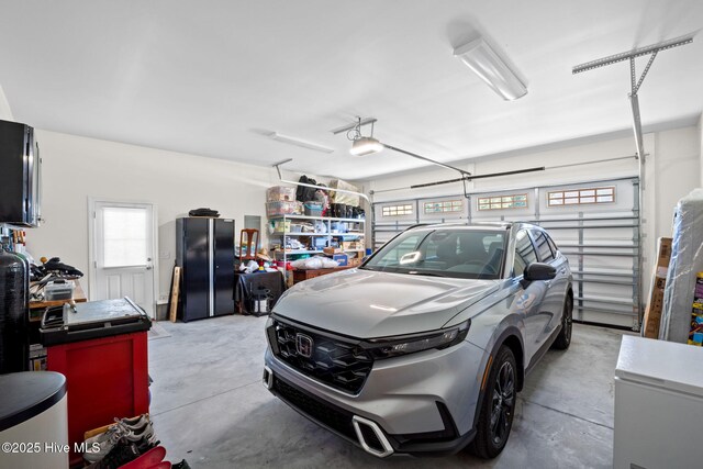 garage with a garage door opener, freestanding refrigerator, and fridge