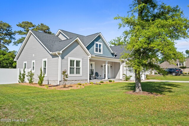 view of front facade with covered porch, a front yard, fence, an attached garage, and a shingled roof