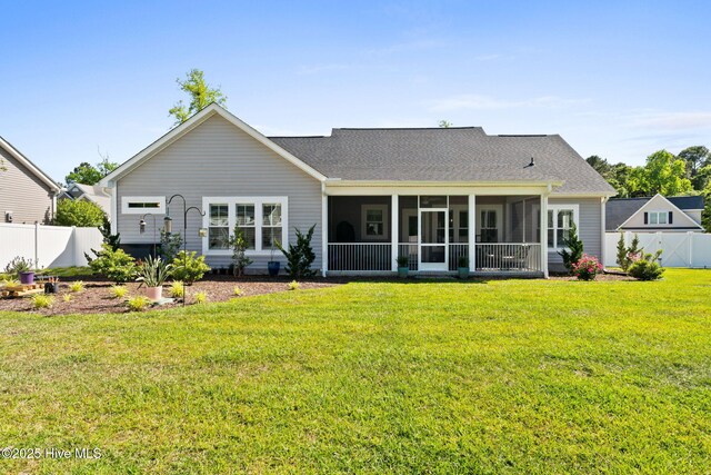 rear view of house featuring a lawn, roof with shingles, fence, and a sunroom