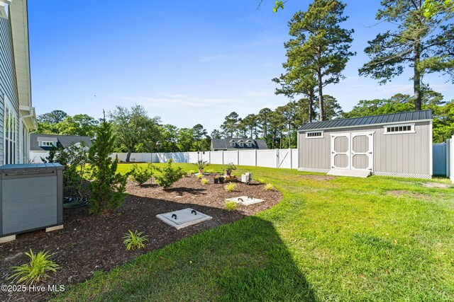 view of yard featuring an outdoor structure, a fenced backyard, and a storage unit