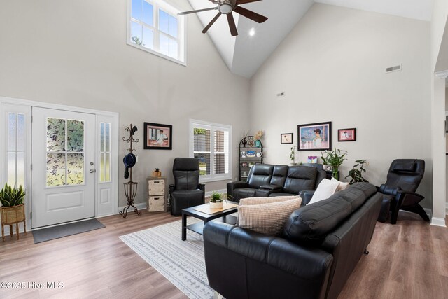 living room featuring ceiling fan, high vaulted ceiling, plenty of natural light, wood finished floors, and visible vents