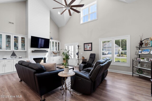 living area with high vaulted ceiling, ceiling fan, wood finished floors, and visible vents
