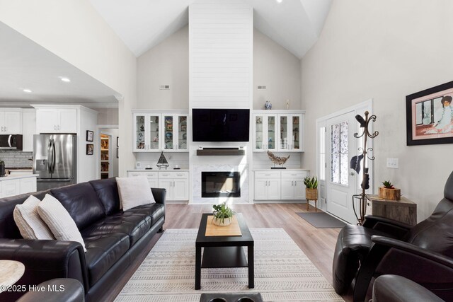 living room featuring light wood finished floors, a fireplace, and high vaulted ceiling
