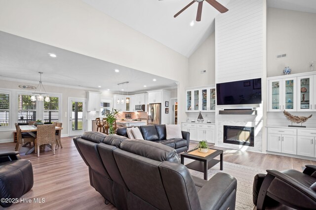 living room featuring recessed lighting, light wood-style floors, ceiling fan with notable chandelier, and a fireplace