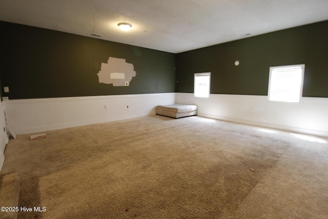 unfurnished room featuring wainscoting and carpet