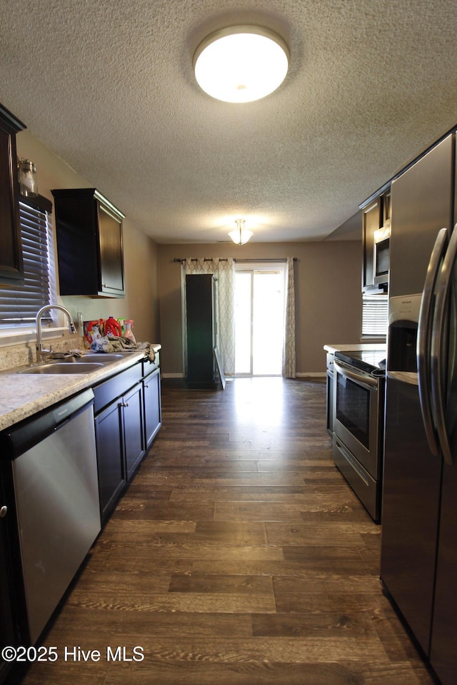 kitchen with a sink, light countertops, stainless steel appliances, and a textured ceiling