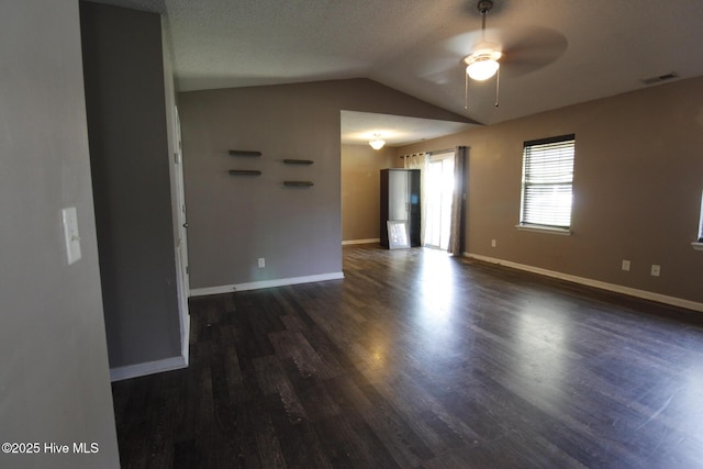 unfurnished room with ceiling fan, baseboards, vaulted ceiling, visible vents, and dark wood-style floors