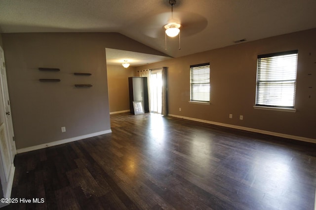 empty room with ceiling fan, baseboards, lofted ceiling, visible vents, and dark wood-style floors