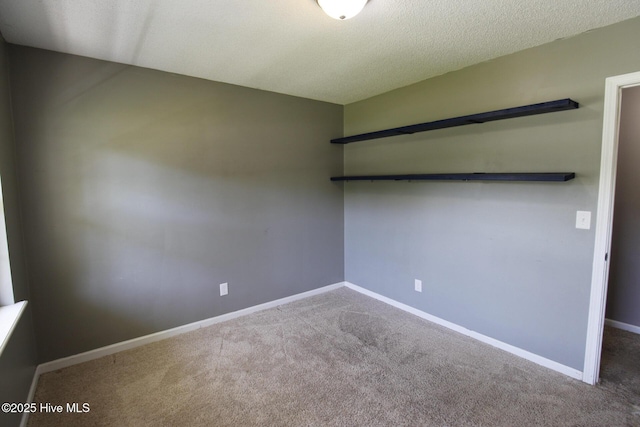 carpeted empty room with baseboards and a textured ceiling