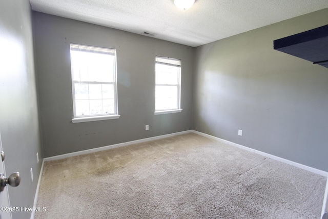carpeted empty room featuring baseboards, a textured ceiling, and visible vents