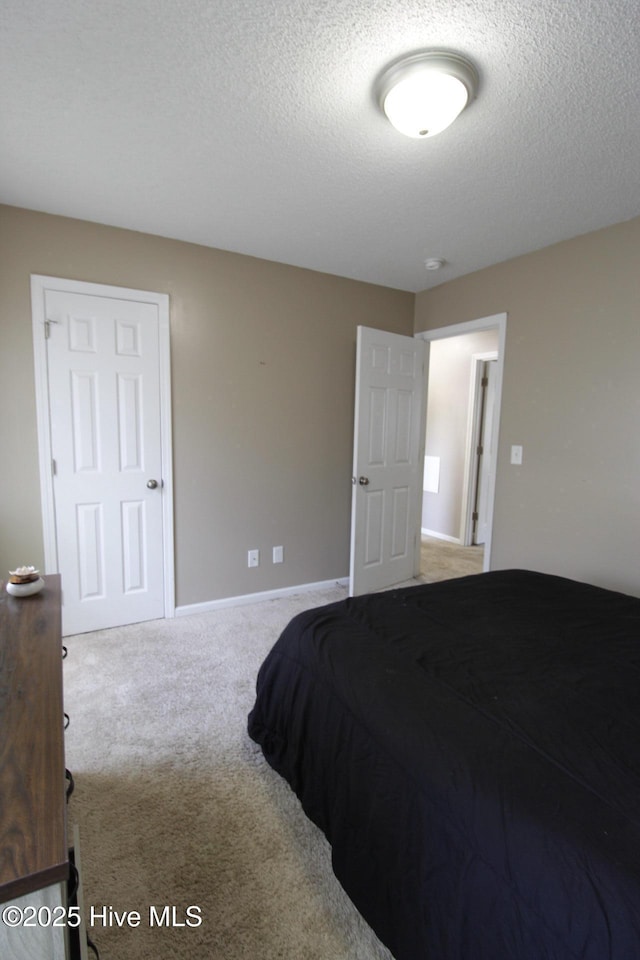 carpeted bedroom featuring a textured ceiling and baseboards