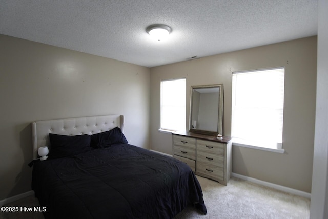 bedroom with a textured ceiling, light carpet, and baseboards
