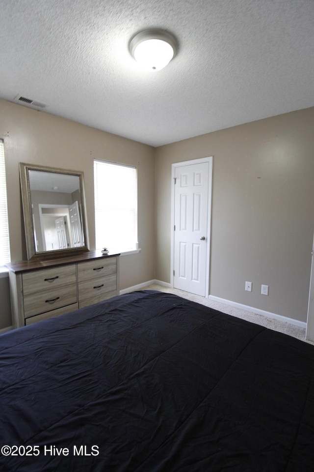 bedroom with visible vents, a textured ceiling, baseboards, and dark carpet
