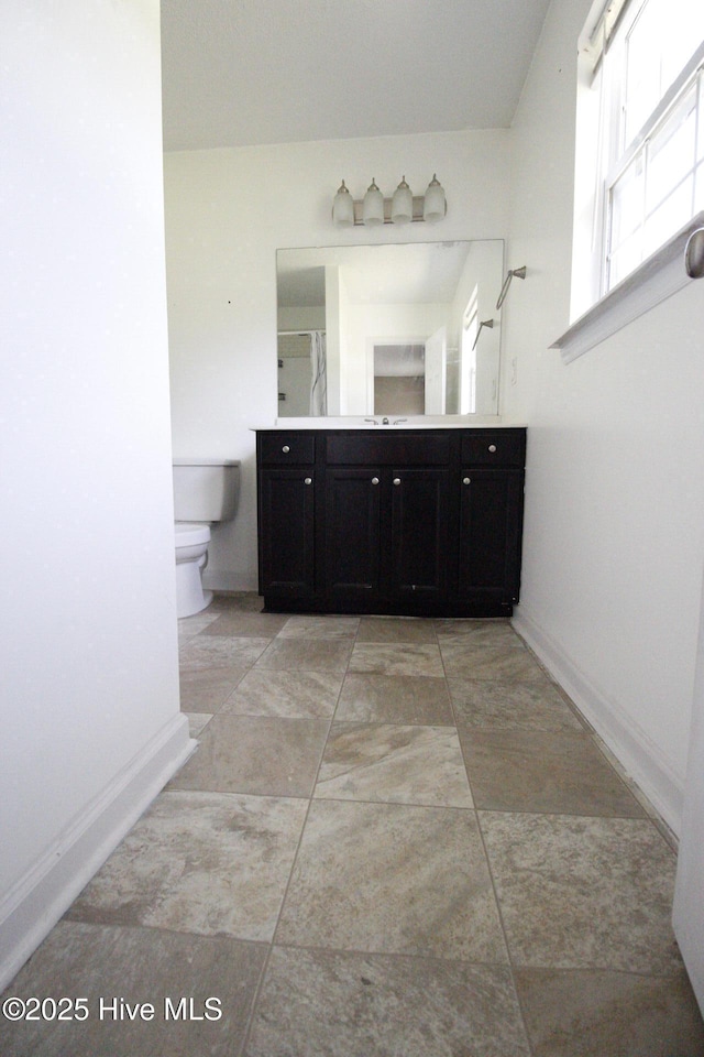 full bath with toilet, baseboards, walk in shower, and vanity