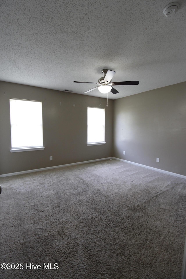 carpeted spare room with baseboards, ceiling fan, and a textured ceiling