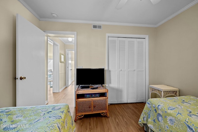 bedroom featuring wood finished floors, crown molding, a closet, and ceiling fan