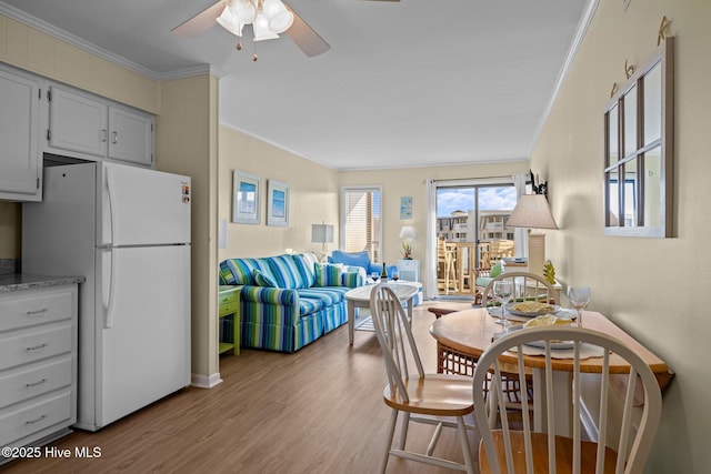 dining area featuring wood finished floors, a ceiling fan, crown molding, and baseboards