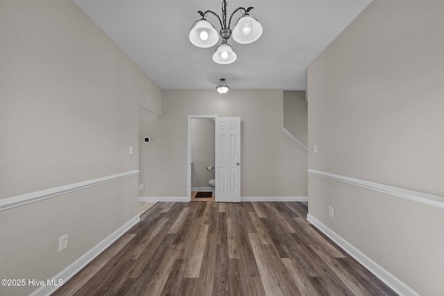 interior space featuring baseboards, wood finished floors, and a chandelier