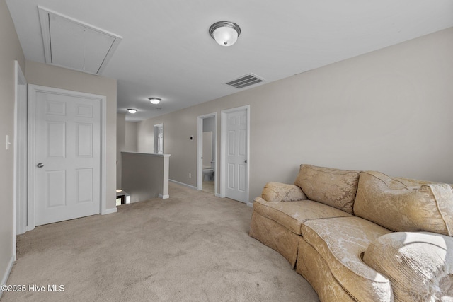 living area with visible vents, attic access, baseboards, and light carpet