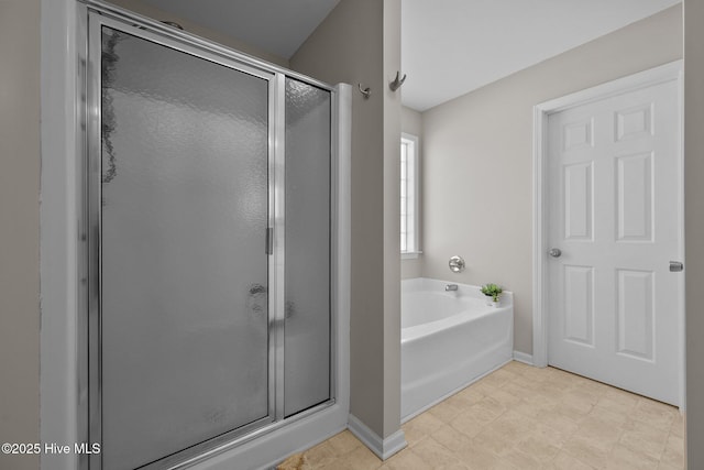 bathroom with baseboards, a stall shower, and a garden tub