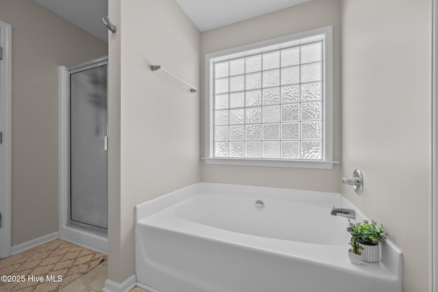 full bath featuring baseboards, a shower stall, and a bath