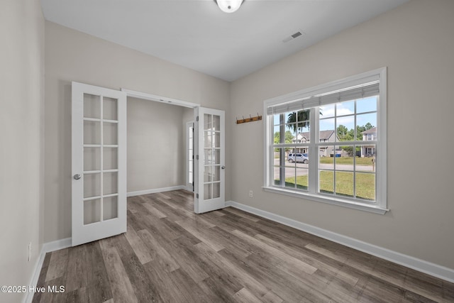 spare room with baseboards, visible vents, french doors, and wood finished floors