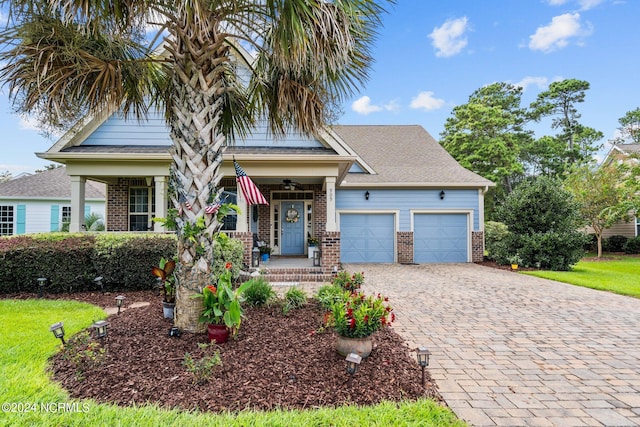 view of front of property featuring brick siding, decorative driveway, an attached garage, and covered porch