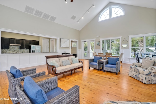 living room featuring track lighting, light wood-style flooring, visible vents, and high vaulted ceiling